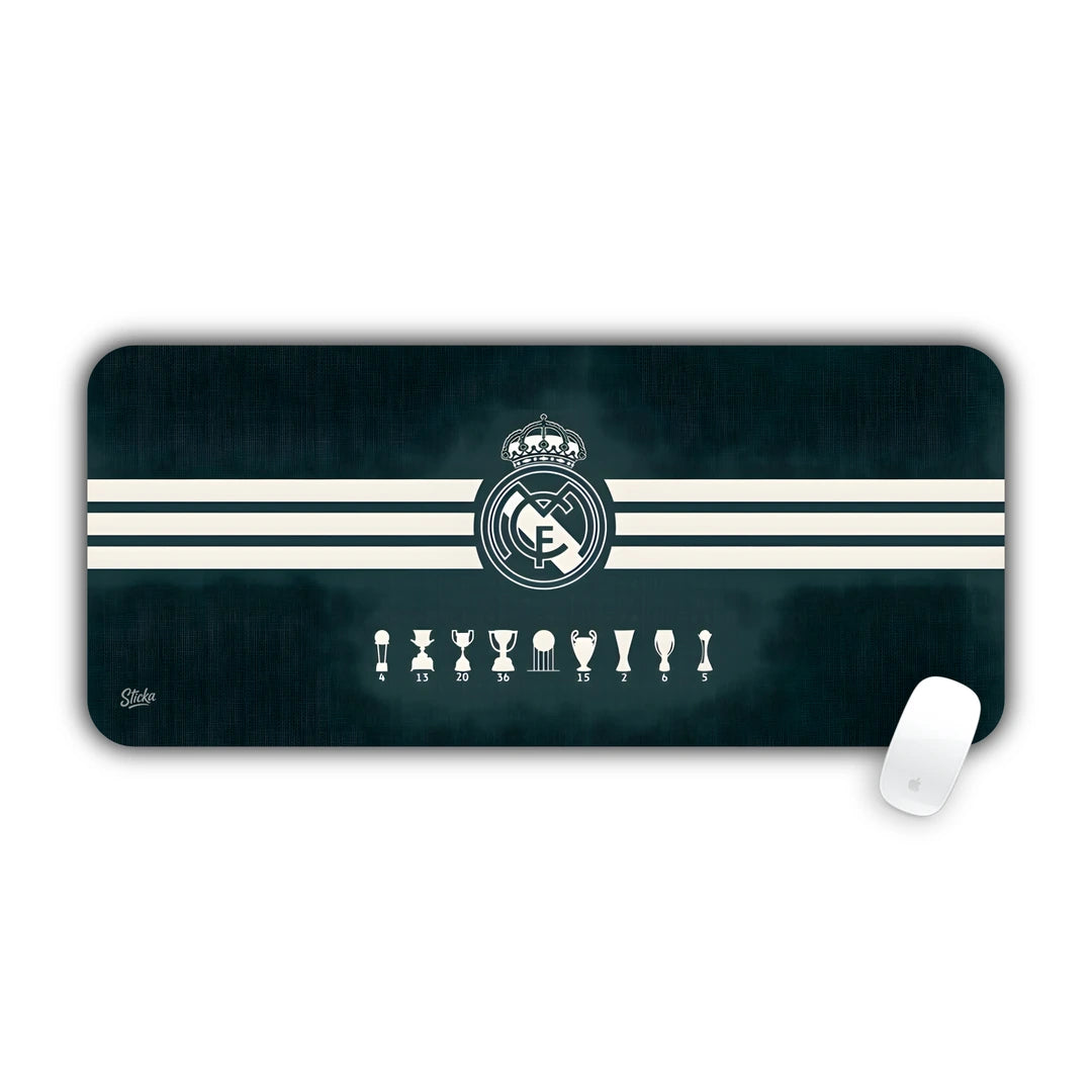Real Madrid crest with European Champions League trophies on dark striped background desk pad 70x30