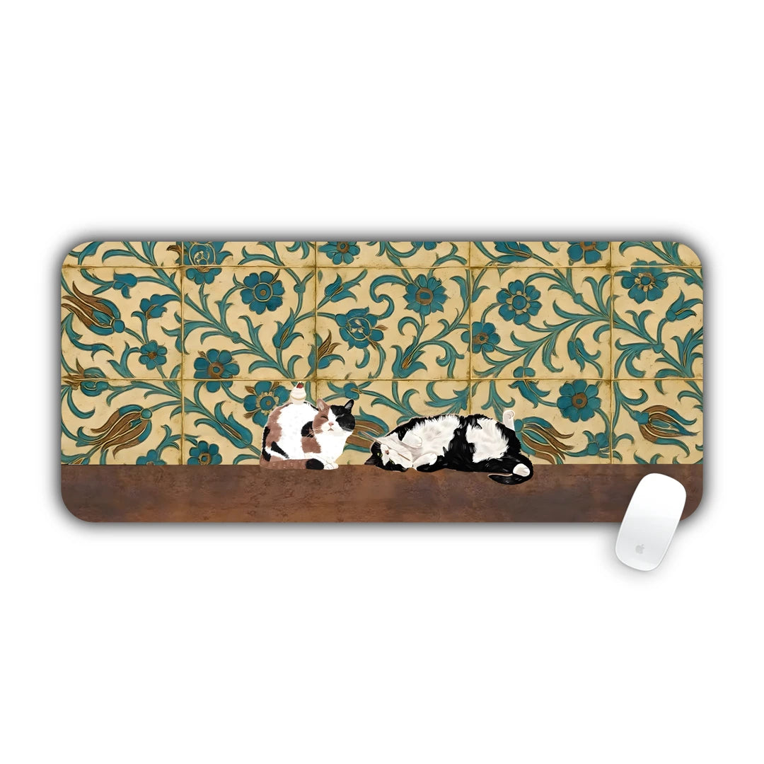 Two calico cats lying in front of a floral green and gold tile wall desk pad 70x30